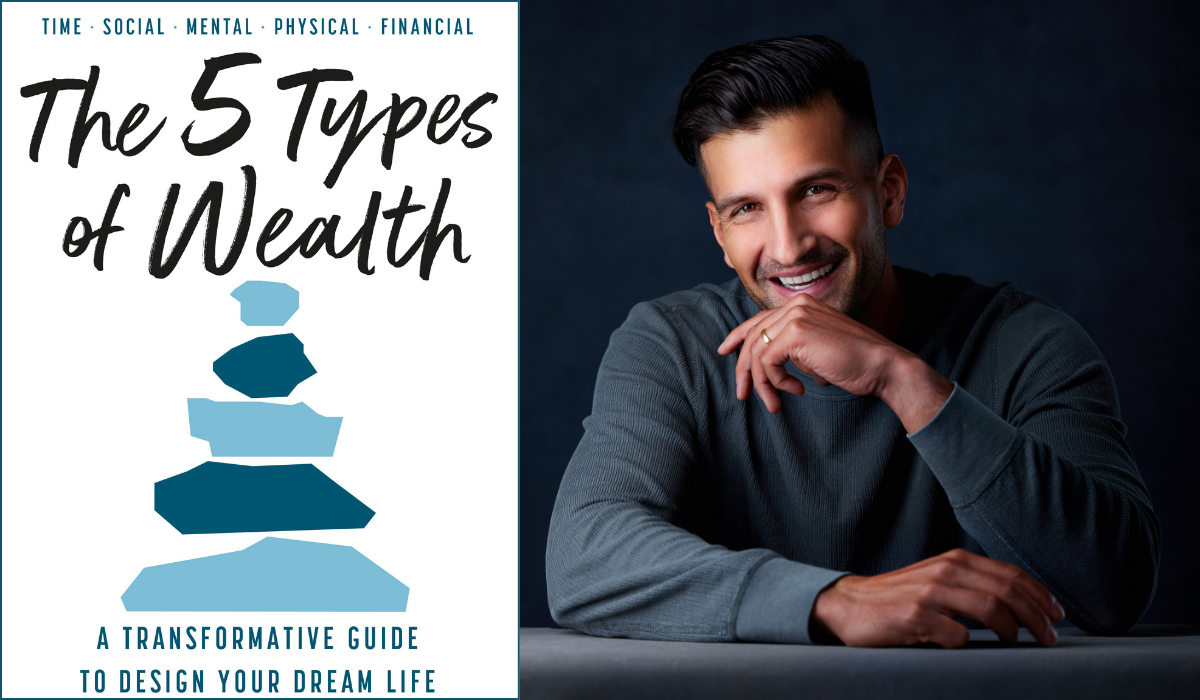 Sahil sits in front of a dark backdrop, resting hands on a table, with a book titled 