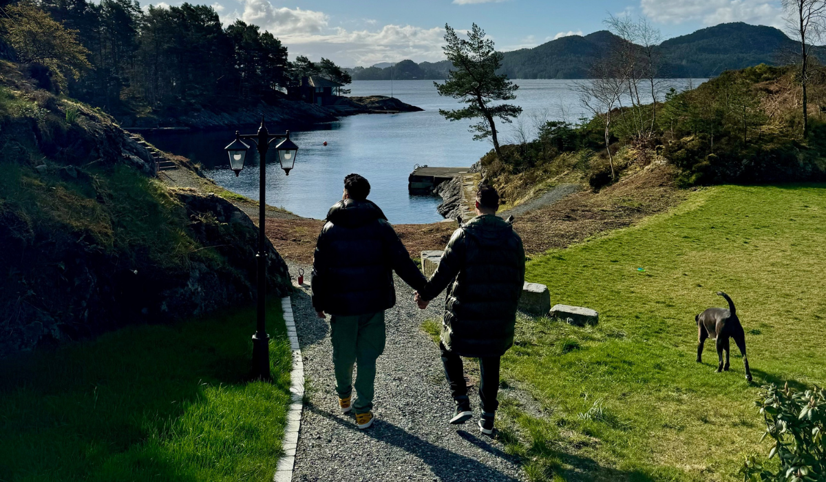 Matt Jacobi-Caprio walks with his partner down a path towards a lake.