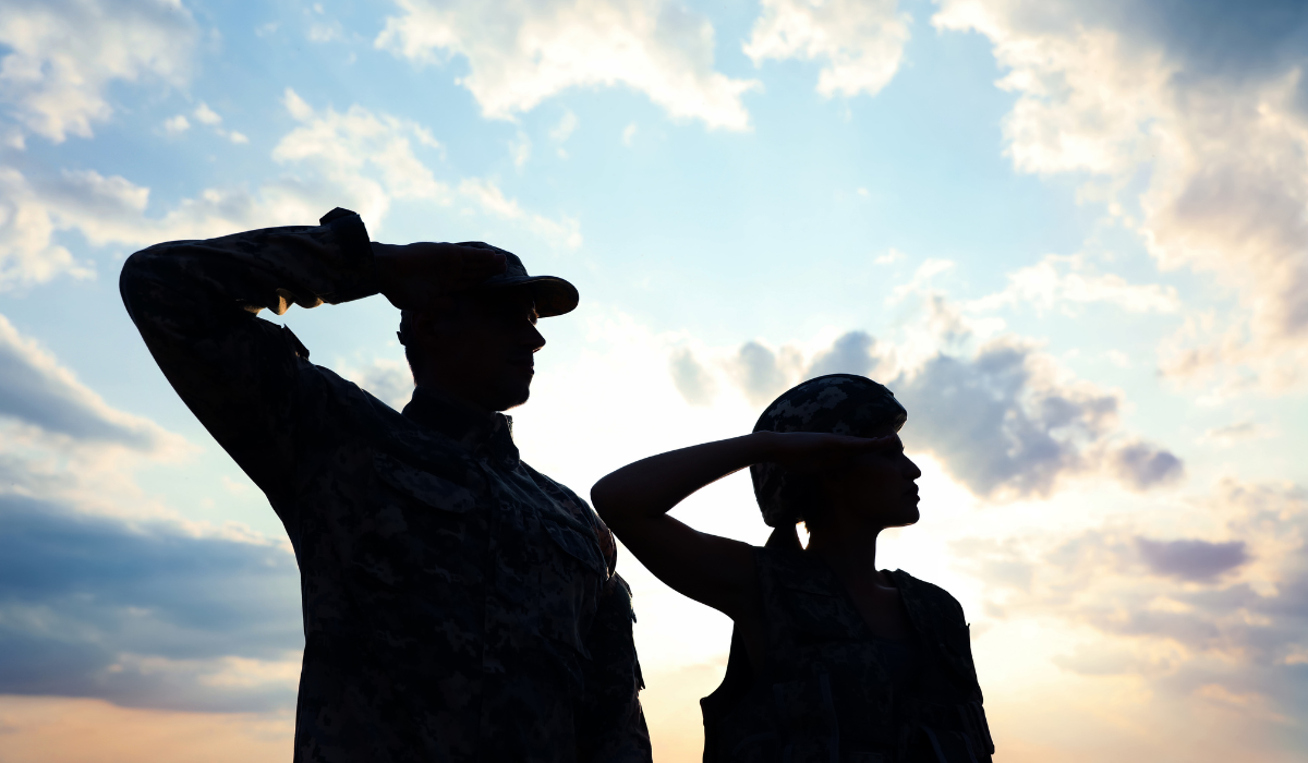 A man and woman in uniform salute.