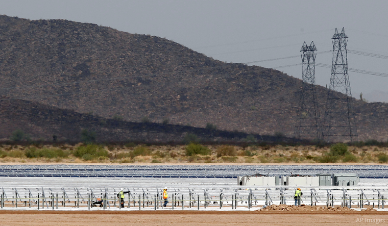 Workers continue to build rows of solar panels at a Mesquite Solar 1 facility under construction in Arlington, Ariz.