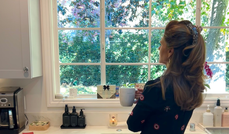 Maria holding a mug, looking out of the window.